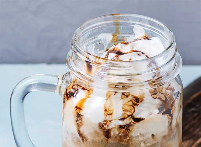 Iced coffee cocktail or frappe with ice cubes and cream in