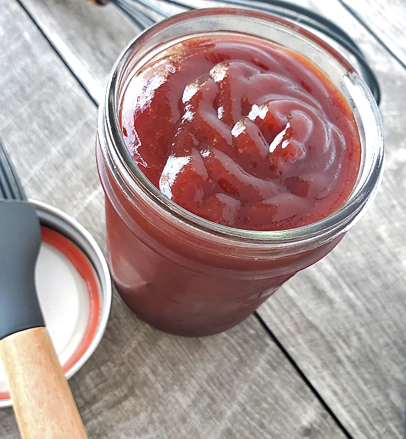 rich thick homemade barbecue sauce in a mason jar with a basting brush for grilling meats