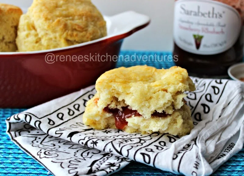 Easy Peasy Buttermilk Biscuits by Renee's Kitchen Adventures on a plate, cut open with jam in the middle. Light and fluffy looking. 