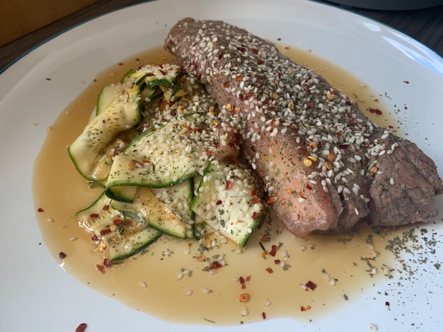 Sirloin steak with courgette ribbons, garnished with sesame seeds, chilli and coriander