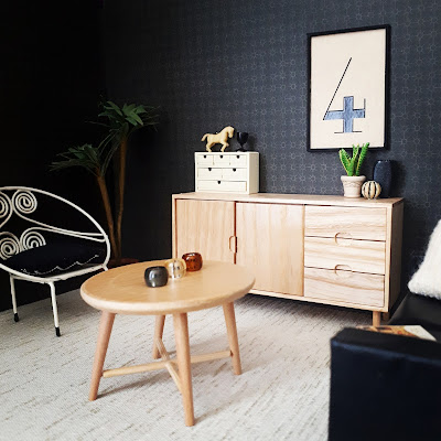 One-twelfth scale modern miniature lounge in cream and black, with a framed printed number four on the wall above a scandinavian sideboard.