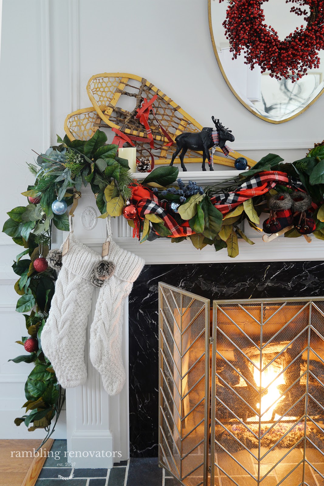 A lush and colourful red and blue Christmas mantel with a plaid scarf, blueberry picks and rustic accents
