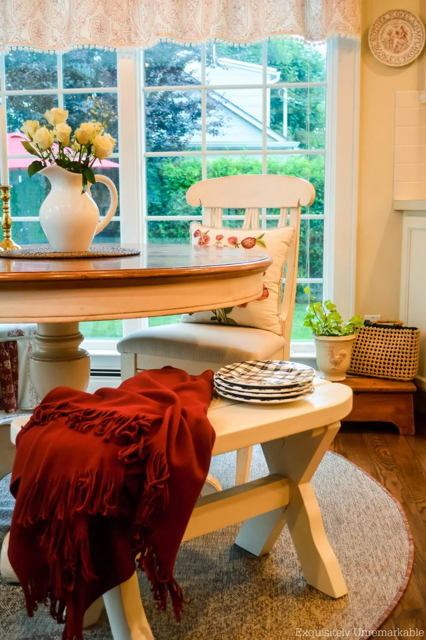 Cottage Kitchen nook with round table and curved bench with throw blanket and black and white plated on top