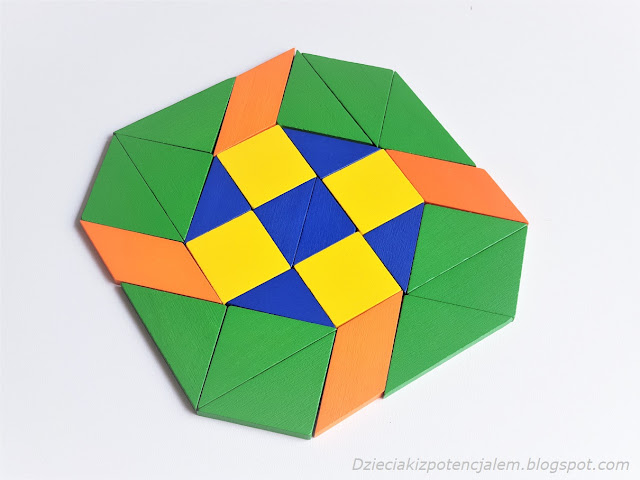 zdjęcie przedstawia mozaikę zbudowaną na kształt mandali z niebieskimi i żółtymi kwadratami wewnątrz, okalanymi przez zielone i pomarańczowe klocki w różnych kształtach 