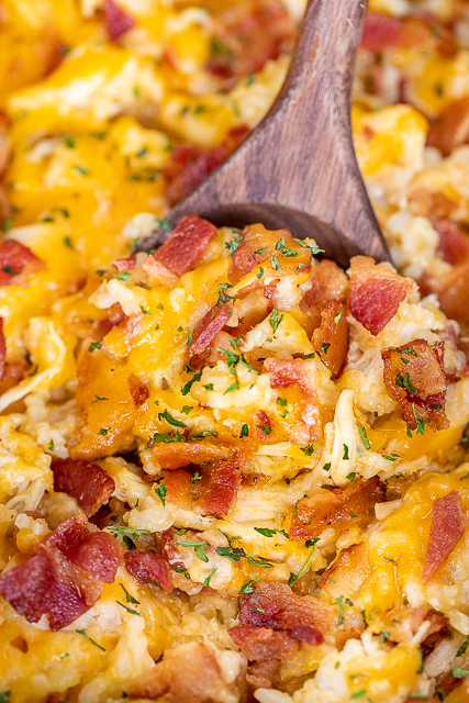 Slow Cooker Crack Chicken and Rice - a quick and easy weeknight recipe! Just dump everything in the slow cooker and dinner is done! Only a few simple ingredients - chicken, ranch dressing mix, bacon, cheddar cheese, cream of chicken soup, milk and rice. Can add some mixed veggies too! Everyone cleaned their plate! Leftovers taste great too! YUM! #crockpot #slowcooker #chicken #rice scooping chicken and rice