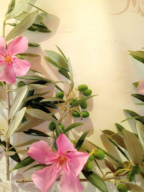 Composición floral con ramas de olivo y flores de adelfa rosa