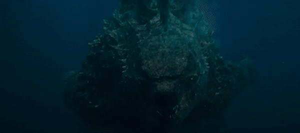 Gif: o monstro Godzilla nadando no fundo do oceano e o King Kong acorrentado pelo pescoço num aparente topo de um prédio rugindo.