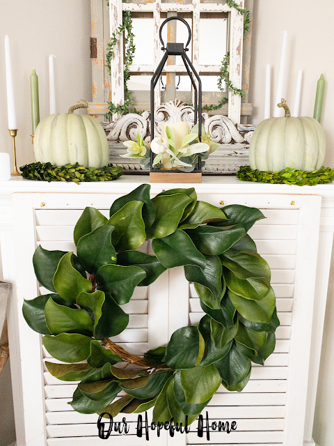 faux magnolia wreath hanging on white shutter