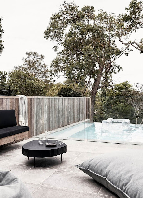 glass pool wall and large stone square patio tiles