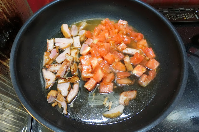 フライパンひとつでつくる湯むきトマトのカルボナーラベーコンに焼き色がつき、にんにくの香りがたってきたらトマト、水を加え、中火で炒め合わせます。 この時、トマトを潰さないように木べらで混ぜ合わせます。