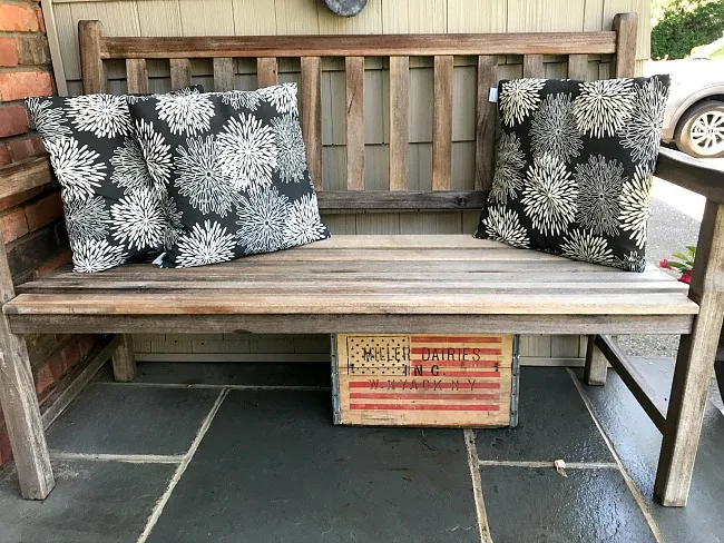 teak bench with flowered pillows