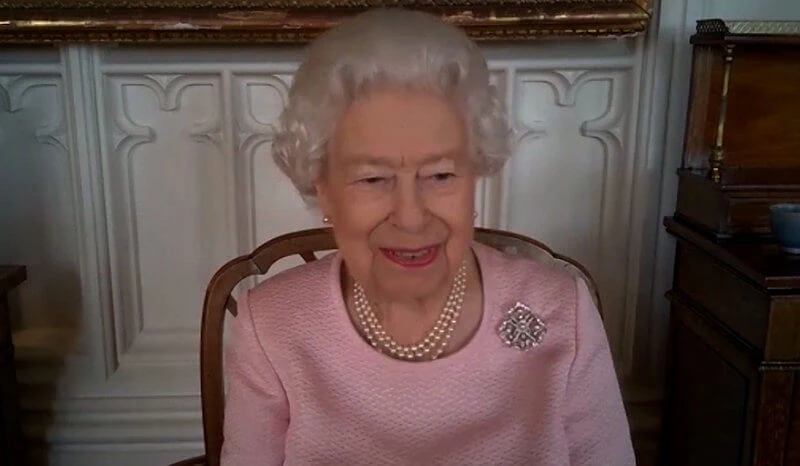 The sculpture depicts Queen Elizabeth in a coat and hat carrying her trademark Launer handbag. diamond silver brooch and pink dress