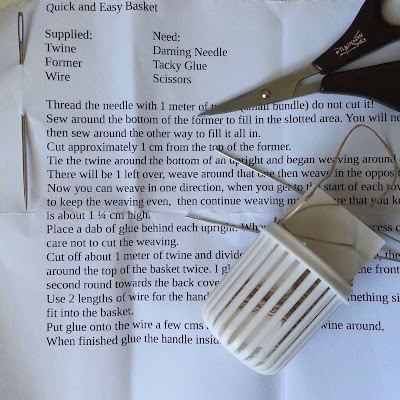 Printed instructions for a one-twelfth scale 'Quick and Easy Basket', with the kit pieces, a pair of scissors and a darning needle laid out on top.