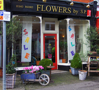 Changing the shop from to attract more passing trade by hanging bright vertical hanging banners in the window, make an ever changing window display like Flowers by S.P florist based in Broadstairs.