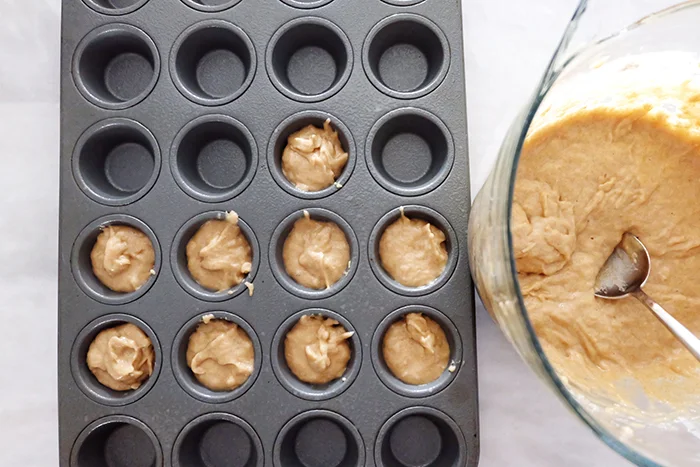 filling muffin tin with pupcake batter