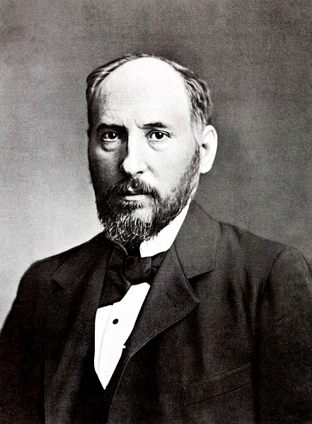 formal black-and-white photo of a bearded, balding man in a dark coat and bow tie