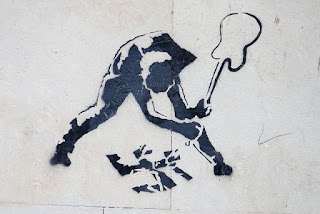 Image of graffiti art showing a person smashing a swastika with a guitar.