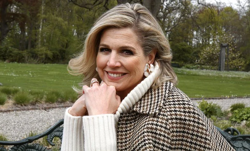 Queen Maxima wore a houndstooth cape by Saint Laurent, and white high neck sweater pullover by Zara, H&M, and floral earrings by Zara