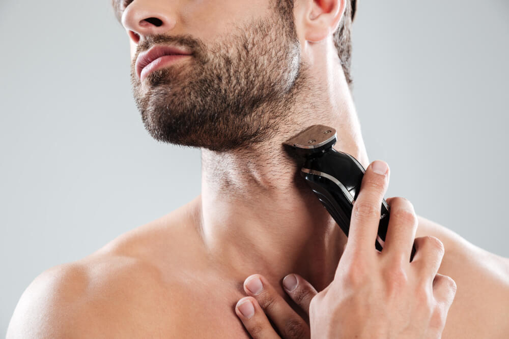 Bearded man using electric razor