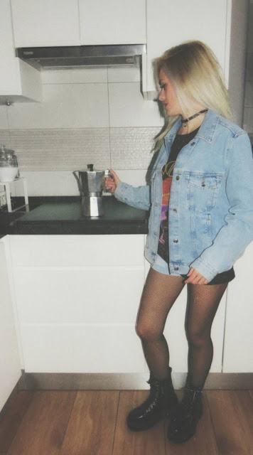 Estilo grunge con camiseta negra ancha con imagen del grupo The Doors, pantalón corto, medias de red pequeña, botas estilo militar y cazadora vaquera