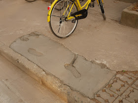 footprints and bicycle tire mark in wet concrete