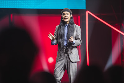 A photo of Ash Chang talking on stage at the event