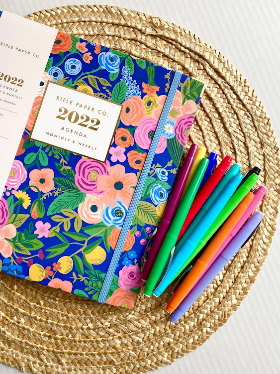 Rifle Paper Co 2022 planner sitting on a placement with colored markers