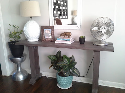 console table styling, west elm brass rhino, plants, metal fan, pineapple lamp, stacked books bamboo mirror, rustic console table