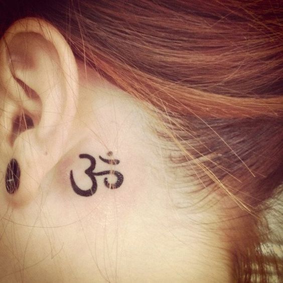 Foto del tatuaje ohm detrás de la oreja de una chica