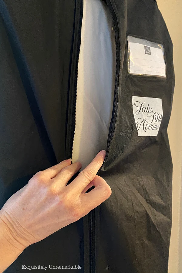 Hand zipping up a black garment bag