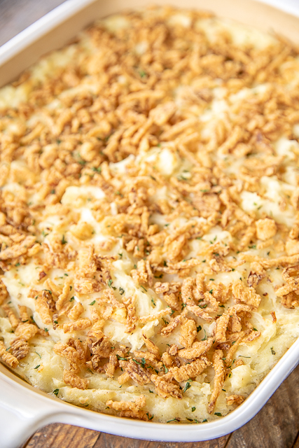 Mashed Potato Casserole - great make ahead side dish for the holidays! SO easy and tastes AMAZING!!! Instant mashed potatoes, hash browns, cream cheese, butter, Monterey Jack cheese, sour cream, garlic, salt, pepper, and french fried onions. Can make in advance and refrigerate or freeze for later. Great for a crowd! #thanksgiving #casserole #makeahead #freezermeal #christmas mashed potatoes in a casserole dish