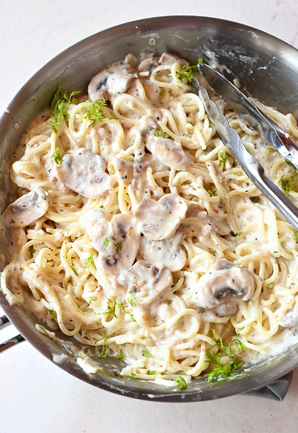 a pan with creamy mushroom pasta topped with chopped parsley and grated parmesan