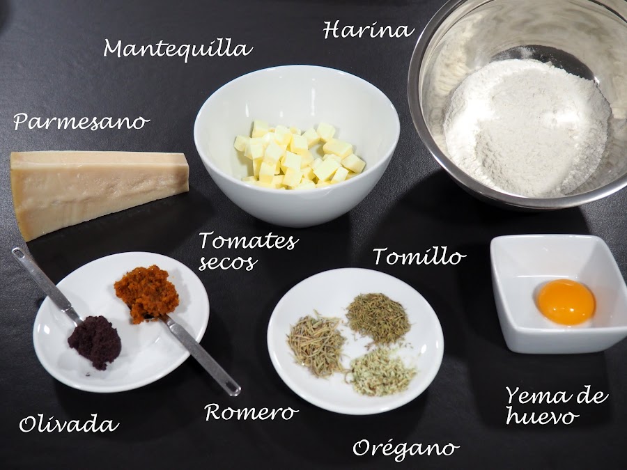 Galletas saladas para aperitivo, con queso parmesano, tomates secos, olivas negras, tomillo, romero y orégano.