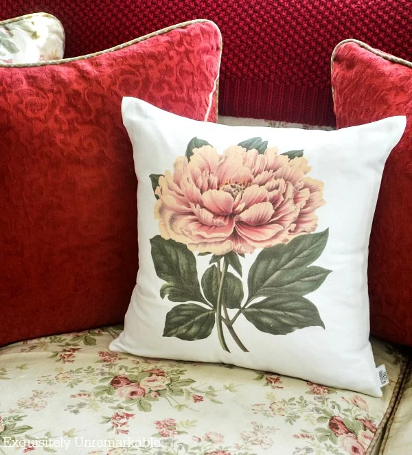 Poppy pillow, red pillows and red throw blanket on a floral couch.