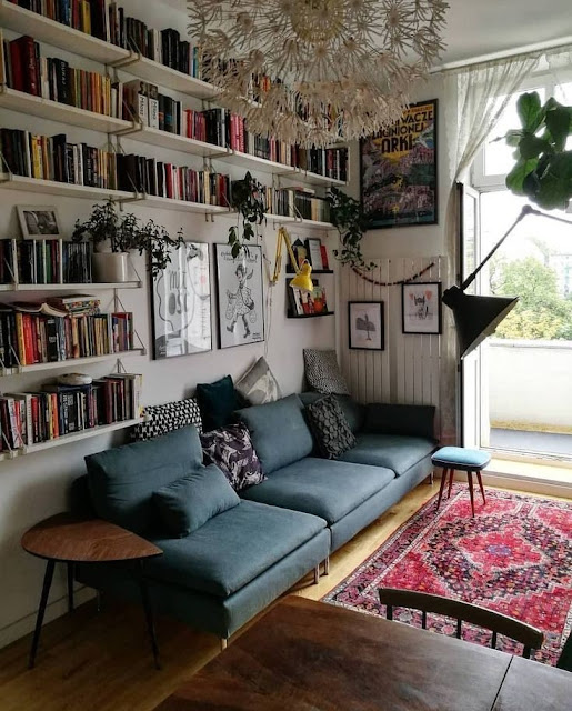 sala de leitura com um sofá grande e aconchegante e prateleiras de livros na parede
