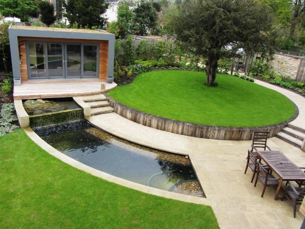 дизайн двора с мощением из камня, прудом и садовым домиком