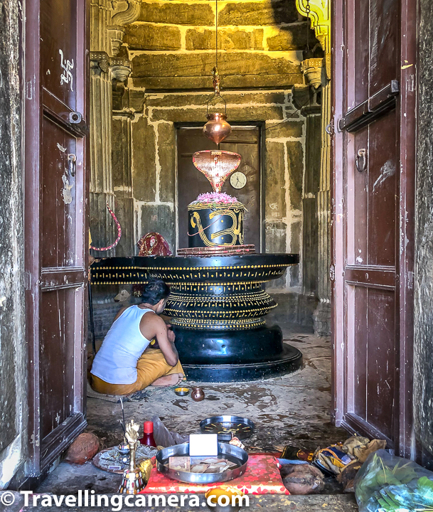 Above photograph shows Shivling inside Neelkanth Mahadev Temple inside Kumbalgarh Fort of Rajasthan. Priest of the temple is decorating the shivling. It was morning time when we went to the temple and that's probably how day of the priest starts after cleaning temple premise.    Neelkanth Mahadev Temple is a famous Shiva temple located inside India's longest wall of  Kumbhalgarh Fort. Supposedly Neelkanth Mahadev temple of Kumbalgarh was built in 1458 AD. This temple has a six feet high monolithic Shivling which are made of stone and dedicated to Lord Shiva.