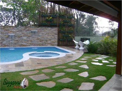 Detalhe da construção da piscina com o piso de pedra Goiás com a parede de pedra, atrás da piscina, com pedra filete de Goiás com execução da cascata da piscina com os caminhos de pedra Goiás e execução da treliça de madeira com eucalipto tratado e a execução do paisagismo.