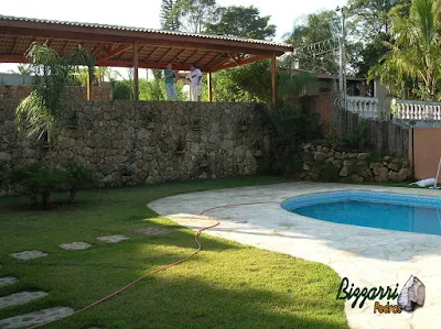 Construção de piscina em residência em Mairiporã-SP com o muro de pedra, o piso com pedra caco de São Tomé e a execução do gramado com grama esmeralda.