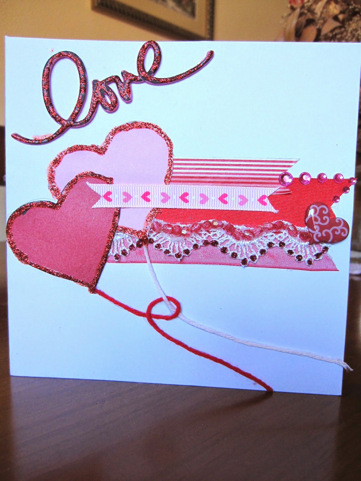 tarjeta scrapbooking de San Valentín en rojo y rosa con dos corazones en forma de corazón entrelazados y la palabra Love