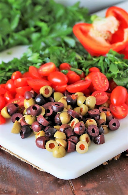 Sliced Olives, Tomatoes, and Chopped Parsley on Cutting Board Image
