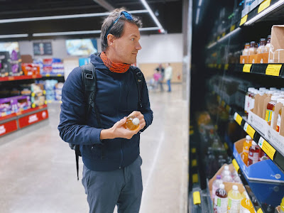 Мужчина выбирает еду в супермаркете | 20 психологических и маркетинговых уловок, которые заставляют нас покупать больше в магазинах