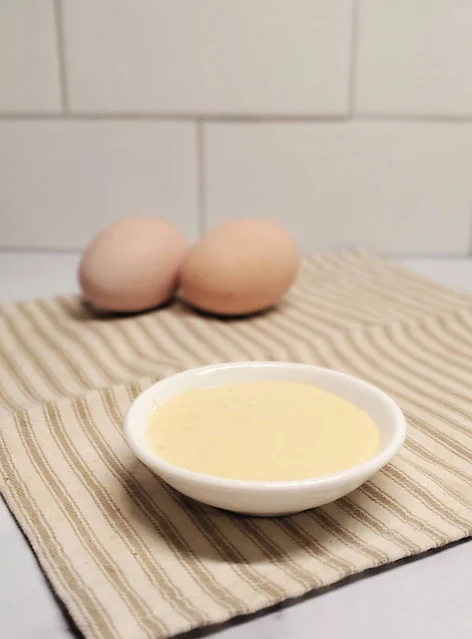two eggs and bowl of dijonnaise on striped towel