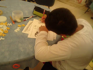 Eduardo trabalhando escrita através do alfabeto móvel e depois escrevendo na folha de atividades