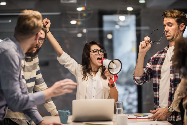 Office workers screaming into a megaphone.