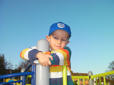 thoughtful pensive boy on park climbing frame, blue sky