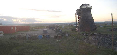 Junk yard with structure built that looks like a Dutch windmill without any blades