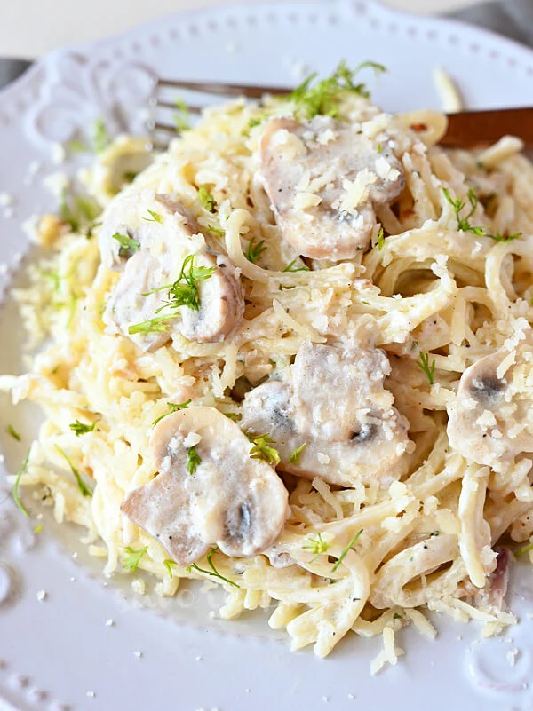 close up of a white plate served with mushroom pasta topped with parmesan