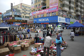 People selling clothes and shoes on the street and store with a large Nokia sign in the background