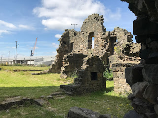 Ruins of castle walls and dockyard buildings and cranes in background. Photo by Kevin Nosferatu for the Skulferatu Project